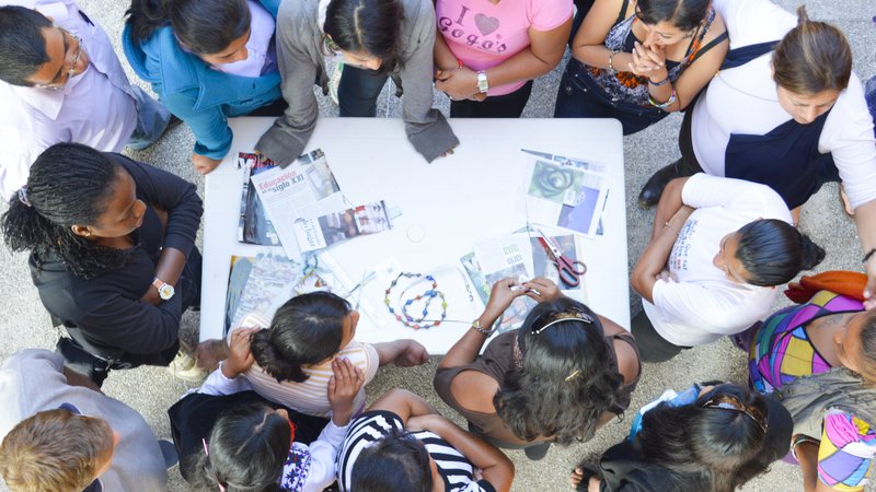 a group of people look over an art board in a circle