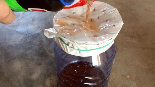 There are two jars. The one with the mosquito on it has colored liquid being poured into it.