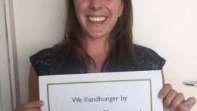 A female Volunteer holds a sign saying she will fight food insecurity by fighting malaria